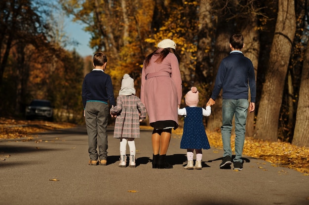 L'arrière de la mère avec quatre enfants sur le parc d'automne.