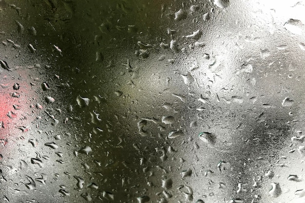 Arrière-plan abstrait avec des gouttes de pluie sur une fenêtre gelée et un ciel nuageux flou
