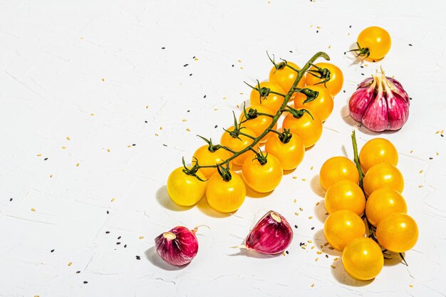 Photo arrière-plan culinaire avec des légumes mûrs tomate jaune cerises ail et graines de sésame