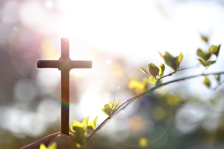 Photo arrière-plan avec des fleurs et des bourgeons de forsythia jaunes et la sainte croix de jésus-christ à la main sur un wa