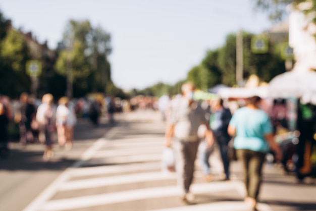 Arrière-plan flou, défocalisation, les gens marchent dans la rue par une journée d'été ensoleillée. Concept de vacances, événement, foule de personnes.