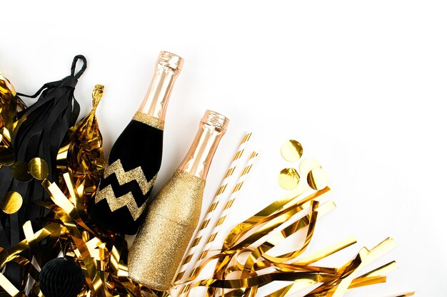 Photo arrière-plan avec guirlande de glands à franges noires et dorées et mini bouteilles de champagne sur fond blanc. mise à plat, vue de dessus. concept de vacances