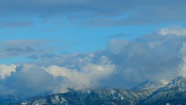 Arrière-plan de la nature sommet de la montagne enneigé avec un nuage blanc se déplaçant avec le ciel bleu en arrière-plan
