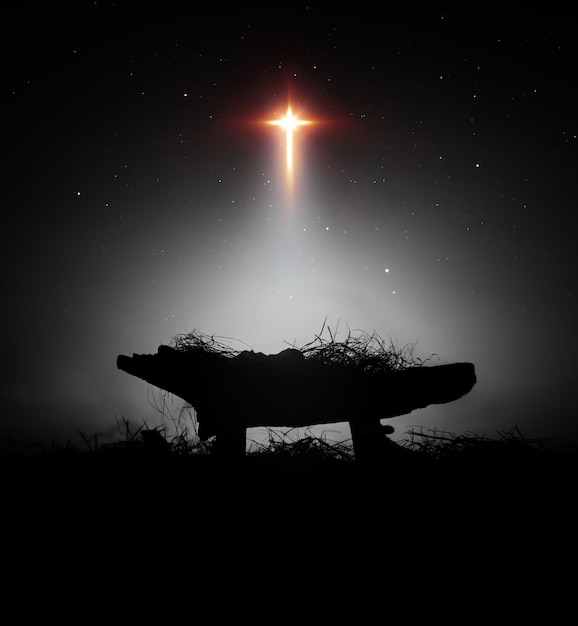 Arrière-plan de Noël avec une grande étoile en forme de croix brillante et le bébé Jésus naît dans la crèche