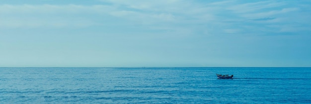 Arrière-plan simple Bateau de pêche en mer bleu foncé calme seul blanc pâle Nuages Spindrift Voie ouverte sans limitations BANNER FORMAT LONG