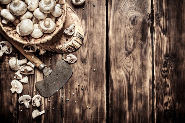 Arrière-plan de style champignons. Champignons frais avec une hache sur un tronc d'arbre. Sur fond de bois.