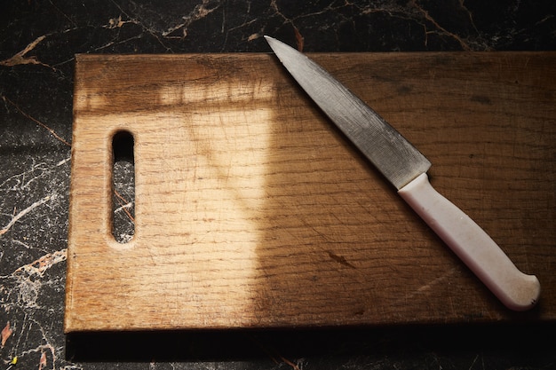 Arrière-plan avec une vieille planche à découper en bois portant sur la table de la cuisine au soleil du matin.