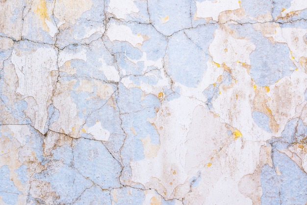 Arrière-plan d'un vieux mur blanchi à la chaux et peint en jaune et bleu avec de la peinture écaillée et des fissures.