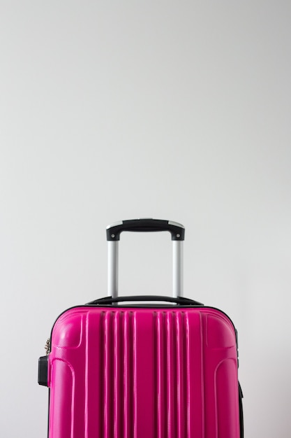 Arrière-plan de voyage - grande valise en plastique rose sur fond blanc avec espace de copie