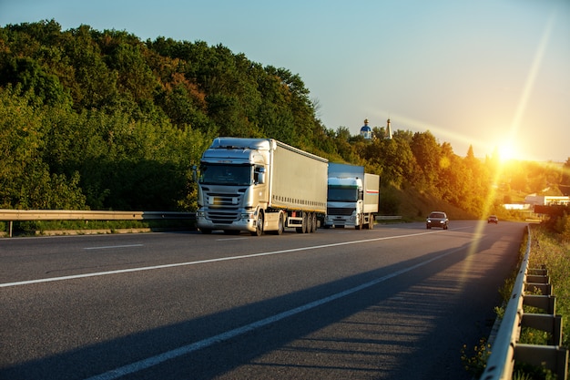 Arrivée d'un camion blanc sur la route dans un paysage rural au coucher du soleil