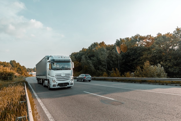 Arrivée camion blanc sur la route dans un paysage rural au coucher du soleil