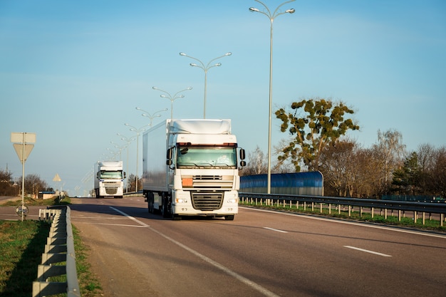 Arrivée du camion rouge sur la route dans un paysage rural au coucher du soleil