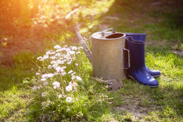 Arrosoir, bottes en caoutchouc et éventreur après le jardinage