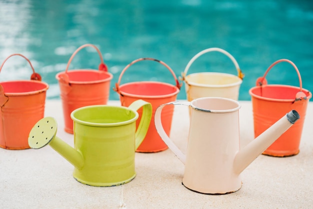 Arrosoirs colorés et seaux pour plantes dans le jardin près de la piscine