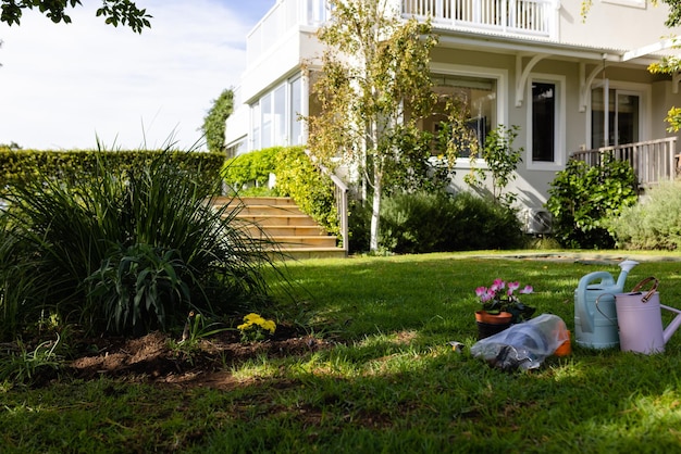 Photo arrosoirs avec pots de fleurs et terre sur terrain herbeux dans la cour à l'extérieur de la maison. concept inchangé, jardinage, biologique et nature.