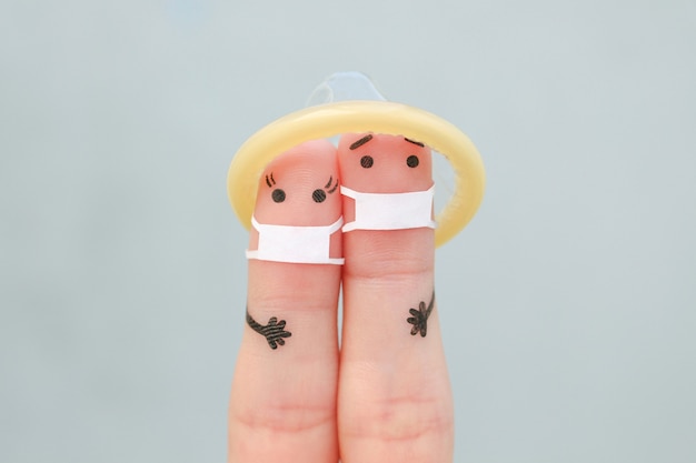 Art de doigt de couple dans des masques médicaux et préservatif