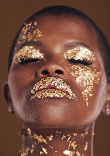 Photo art doré et visage de femme noire avec maquillage pour l'esthétique de la beauté isolé dans un studio fond marron yeux fermés luxe créatif et personne africaine avec glamour cosmétique ou design pour les soins de la peau