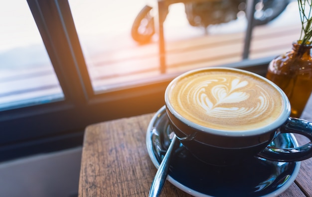 Art du café latte dans une tasse sur la table en bois.