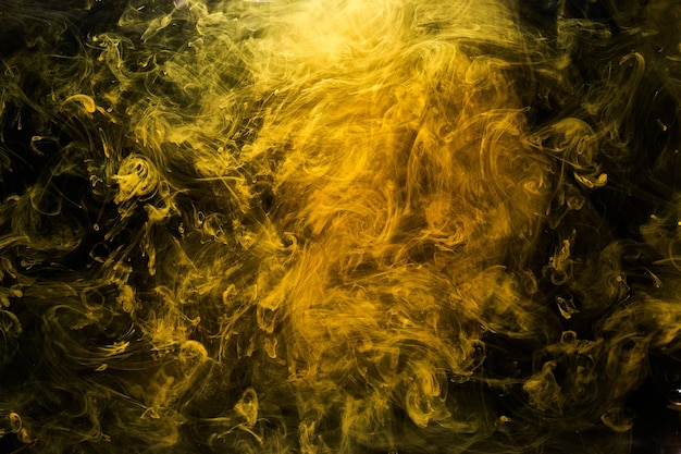 Photo art liquide abstrait, bombe fumigène jaune sur fond noir, peintures acryliques de couleur ambre sous l'eau