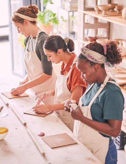 Photo l'art de la poterie et les personnes créatives s'alignent dans l'atelier sculptant ensemble pour le processus de production et la productivité concentration et compétence de l'équipe interraciale de femmes occupées dans l'espace de travail