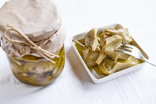 Artichaut mariné à l'ail dans une assiette blanche sur la table avec nappe blanche