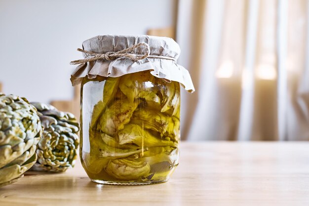 Artichauts fermentés conservés dans de l'huile d'olive dans des bocaux en verre sur une table en bois