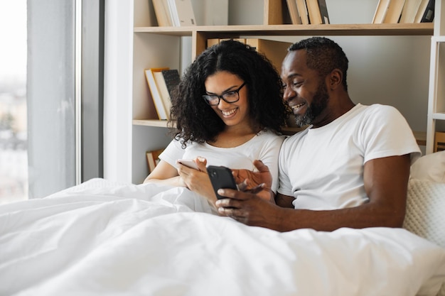 Article de lecture de famille multiraciale sur les smartphones au lit