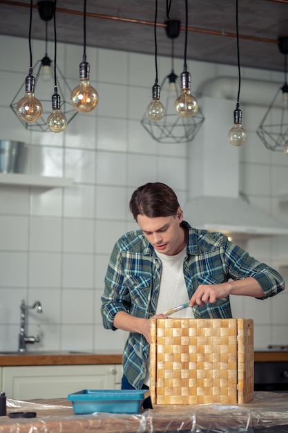 Artisan concentré peignant le bord de la boîte en bois