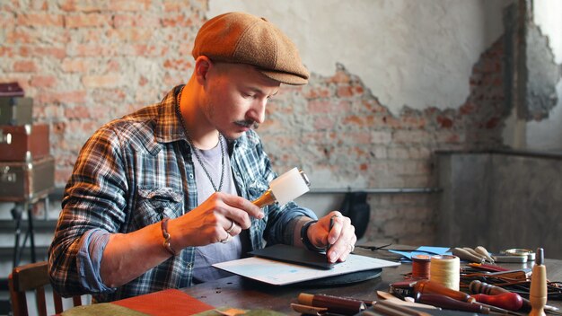 Artisan Dans Son Atelier Fabrique Un Portefeuille En Cuir. Le Concept De La Production Artisanale De Produits En Cuir Véritable Faits à La Main