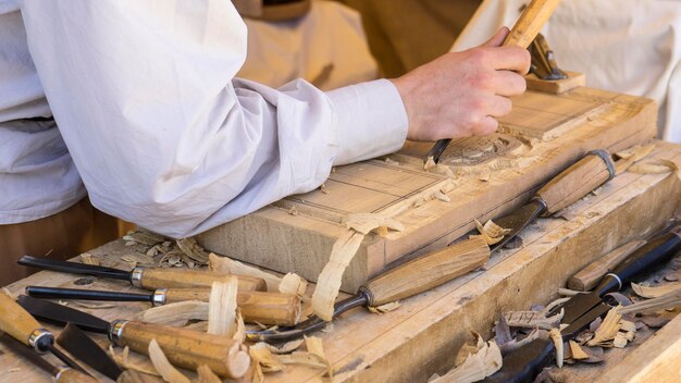 artisan découpant du bois dans une foire médiévale, outils de menuiserie