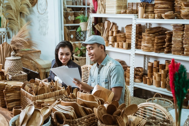 Un artisan donne un croquis d'article en papier à une femme d'affaires dans un atelier d'artisanat