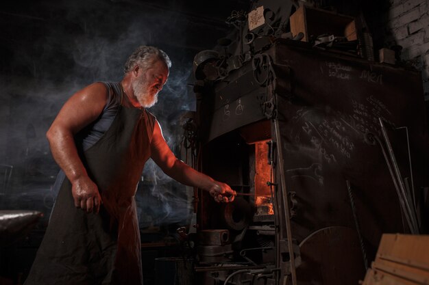 Artisan forgeron en tablier travaille dans la boutique du forgeron