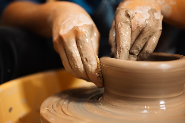 Artisan professionnel potier faisant cruche d'argile sur cercle de roue de potier en atelier