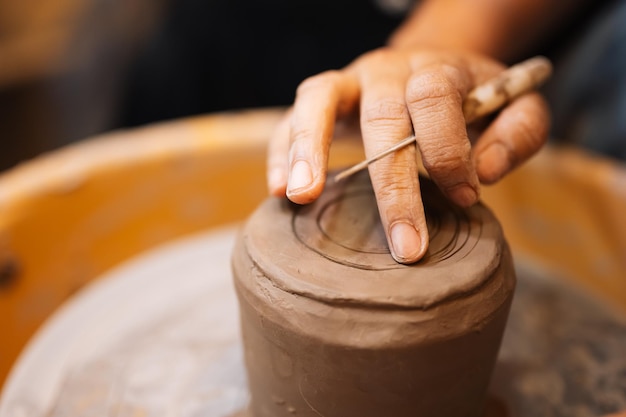 Artisan professionnel potier faisant cruche d'argile sur cercle de roue de potier en atelier