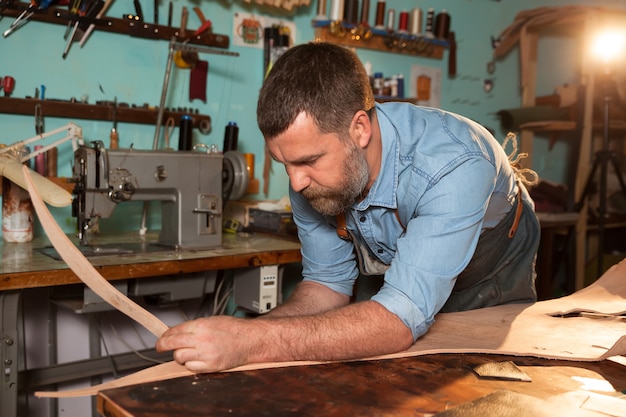 Artisan en tablier travaillant le cuir à l'atelier