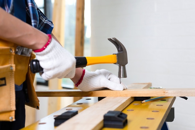 Un artisan utilisant un marteau clouté en atelier, un charpentier utilisant le marteau a frappé un clou pour assembler du bois dans un atelier de menuiserie