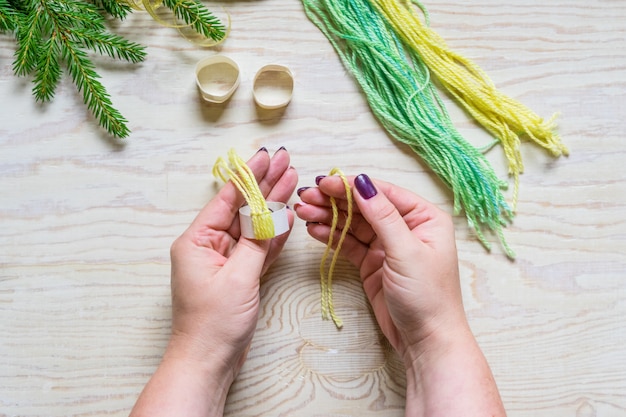 Photo artisanat d'hiver bricolage, petit bonnet. formez et serrez le nœud sur l'anneau en papier.