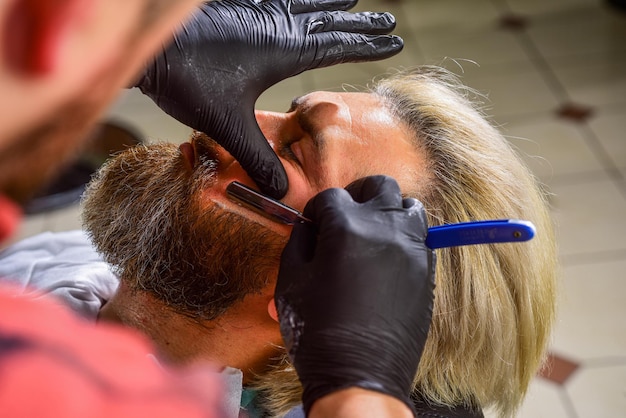 Artisanat maîtrisé en coupant les cheveux tous les jours. Visite chez le coiffeur. Maintien de la forme. Homme au salon de coiffure. Cliente du salon de coiffure. Tailler la barbe. Services de salon de coiffure. Aspect parfait. Rasage des poils du visage.