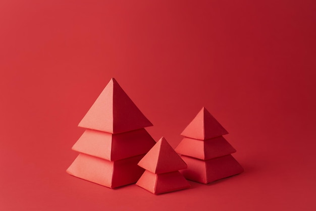 Artisanat de Noël en papier, carte de Noël, trois arbres de Noël en papier rouge sur fond rouge.