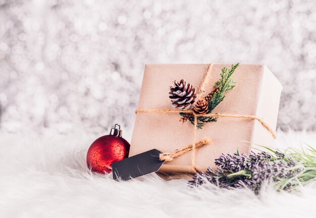 Artisanat en papier brun gondolé sur la boîte présente avec étiquette, décorer avec pomme de pin et christm