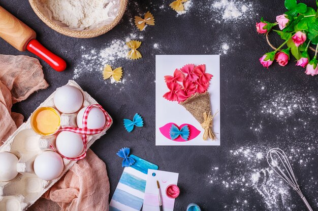 Artisanat en papier pour la fête des mères, le 8 mars ou l'anniversaire. Petit enfant fait un bouquet de fleurs en papier coloré et pâtes colorées.