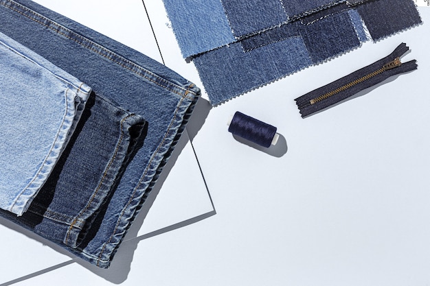 Artisanat, réparation de vêtements. Accessoires de couture de jeans bleus déchirés avec un fond coloré d'en haut. Mise à plat