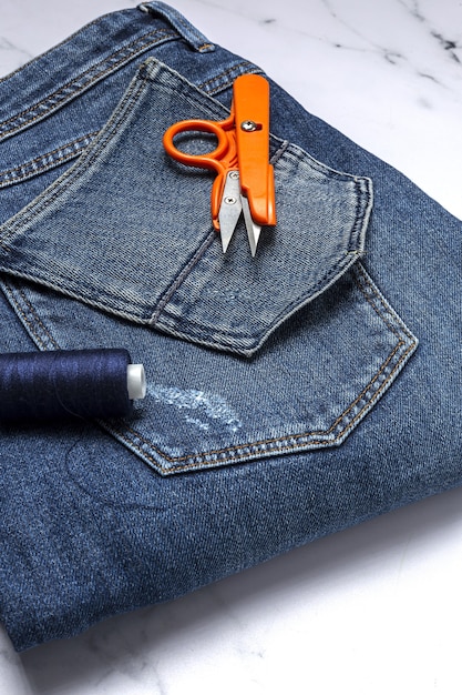 Artisanat, réparation de vêtements. Accessoires de couture de jeans bleus déchirés avec un fond coloré d'en haut. Mise à plat