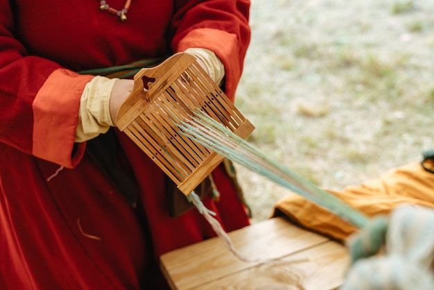 Artisanat de tissage. Femme en costume traditionnel travaille avec les mains