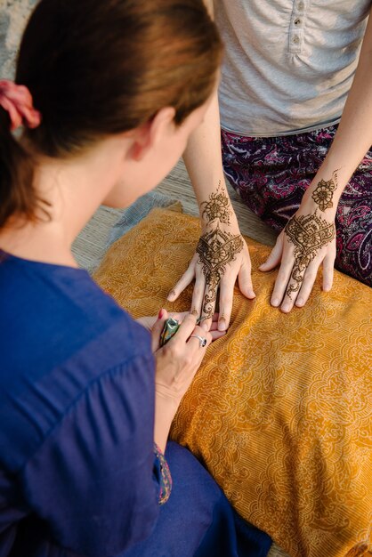 Artiste appliquant le tatouage au henné sur les mains des femmes. Le mehndi est un art décoratif indien traditionnel. Du point de vue de l'artiste