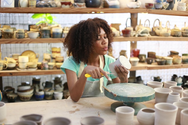 Artiste céramiste peignant la surface extérieure d'un morceau de poterie