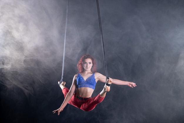 Artiste de cirque aérien athlétique, sexy et flexible avec une rousse sur des sangles aériennes.