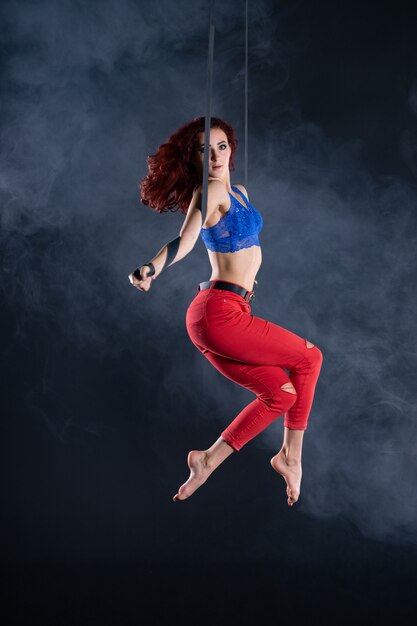 Artiste de cirque aérien flexible sexy athlétique féminine dansant sur la soie