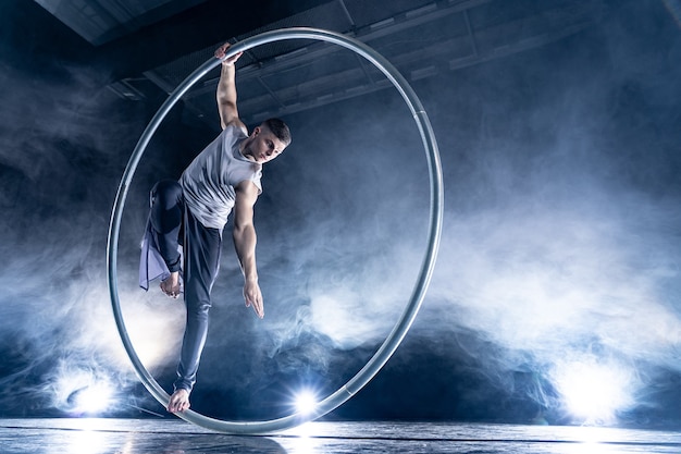 Artiste de cirque Cyr Wheel sur fond sombre et fumé sur scène