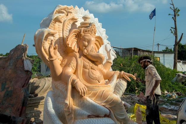 Artiste faisant une statue et donne la touche finale à une idole du dieu hindou Lord Ganesha lors d'un atelier d'artiste pour le festival Ganesha